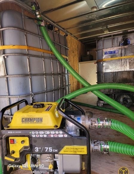 Champion gas-powered generator with green hose connected inside a utility truck bed with metal storage containers and equipment